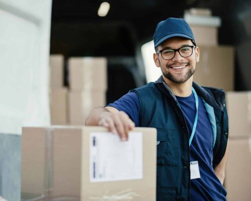 young-happy-delivery-man-with-cardboard-boxes-looking-at-camera-.jpg